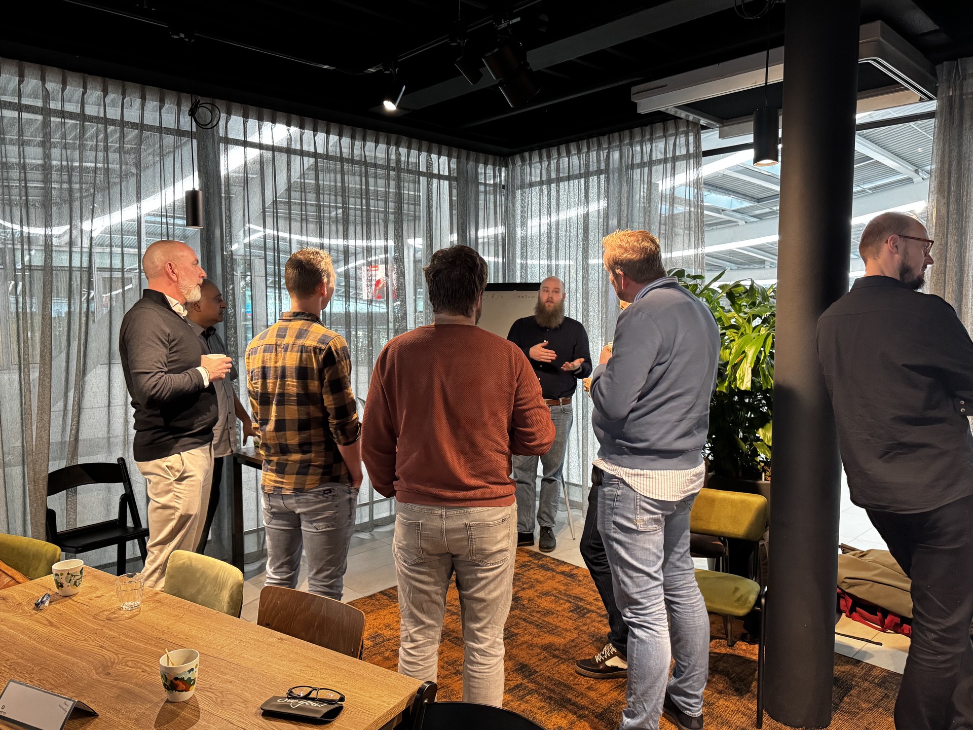 Workshop setting in een kantoor waar 6 mensen luisteren naar Erik.
