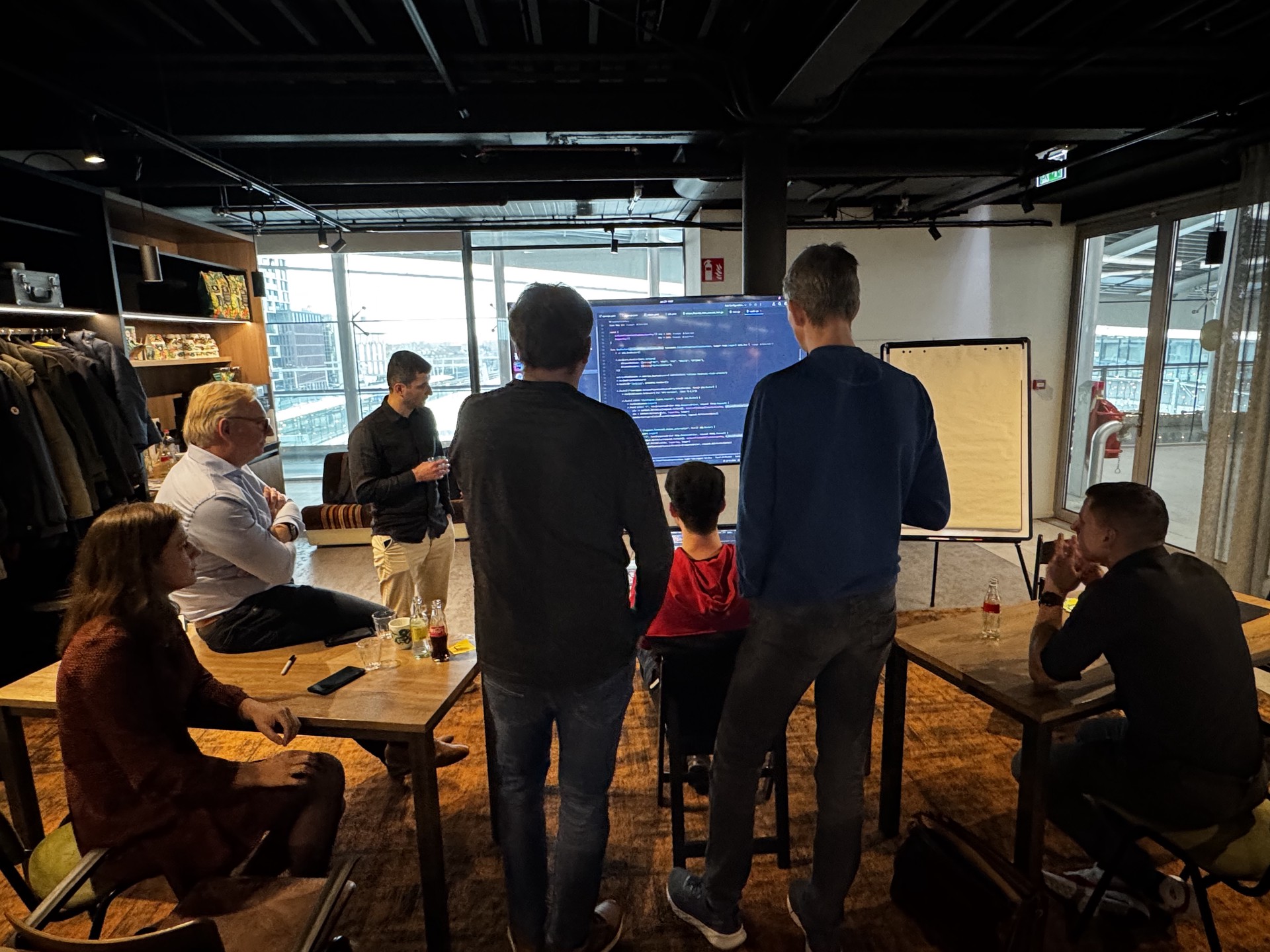 Workshop setting in een kantoor waar 6 mensen kijken naar het scherm en luisteren naar Daan.