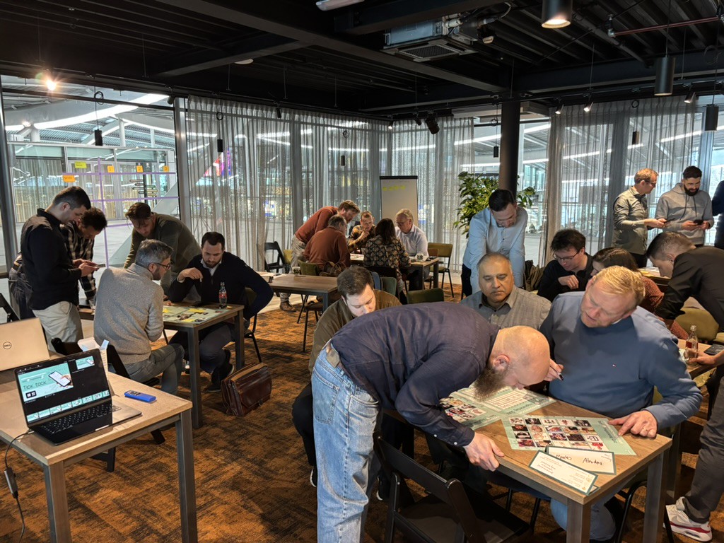Grote groep mensen aan verschillende tafels die een quiz oplossen.